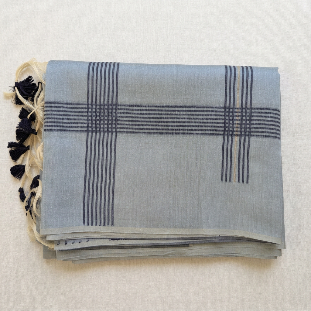 Folded saree on a soft off-white linen background in a square composition